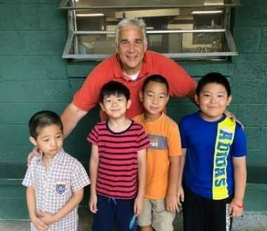 Adult and campers posing together in front of a green wall at Athens YMCA Camps