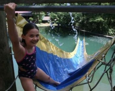 Camper sitting at the top of a lake slide at Athens YMCA Camps