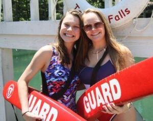 Two lifeguards holding rescue tubes by the waterfront at Athens YMCA Camps